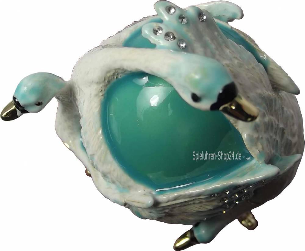 Blick von oben auf die weißen Schwäne, die das Ei zu bewachen scheinen